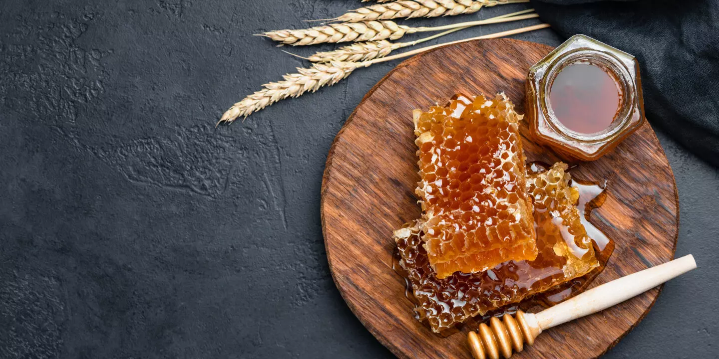 Eine Honigwabe  neben einem Honigglas